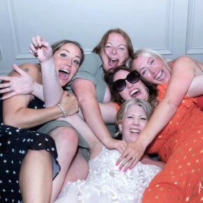 The bride larking around with her girlfriends in the bar at her Pendley Manor Hotel wedding