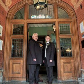 The groom and best man in the grand main entrance doorway at Pendley Manor Hotel