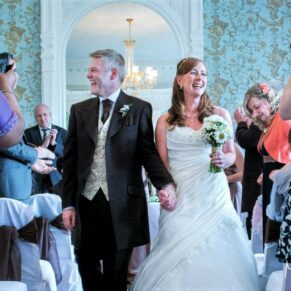 The newlyweds exit the indoor ceremony with big smiles at their at Pendley Manor Hotel wedding