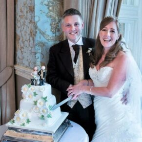 The newlyweds cutting the cake in the Oak Room during their Pendley Manor Hotel wedding reception