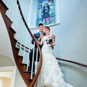 Sir Christopher Wren Hotel Wedding Photography - the bride and groom pose for a picture on the hotel's main staircase
