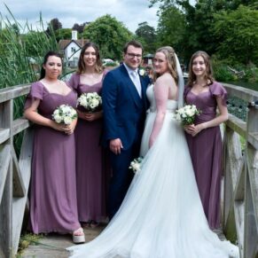 Swan at Streatley wedding photography - the newlyweds pose for the camera on the bridge with their bridesmaids