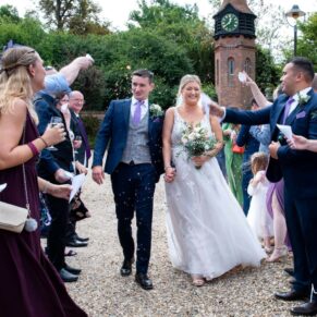 The bride and groom face a barrage of confetti from their guests as they are cheered through the aisle
