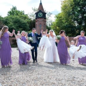 The bridal party walking together in front of the venue's clock tower