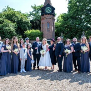 Large family group pose in front of the clock tower at the Tudor Barn in Burnham