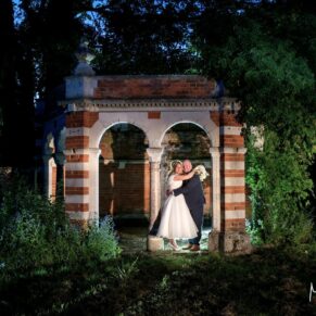 The newlyweds in a dramatic pose at dusk in the Tudor Barn's floodlit follyly