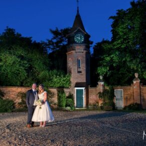 The Tudor Barn floodlit at dusk with the newlyweds positioned in the foreground for a dramatic capture