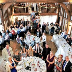All of the wedding guests inside the barn as seen from the balcony at the Tudor Barn in Burnham