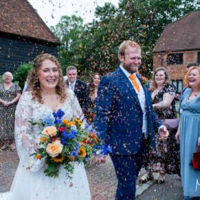 The newlyweds walk through their confetti aisle with the guests cheering them on loudly at their Olde Bell Hotel wedding reception in Hurley