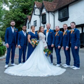 The smiling wedding bridal party pose for the camera outside the Olde Bell Hotel in Hurley