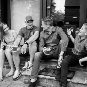 Some of the wedding guests sat on the steps enjoying the relaxed drinks reception at The Olde Bell hotel in Hurley