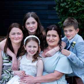 Relaxed family portrait of five wedding guests captured outside the historic barn at The Olde Bell in Hurley