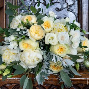 Gorgeous bride's white and yellow wedding bouquet placed on an antique wooden carved chair in the gardens at The Olde Bell in Hurley