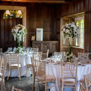 Dramatic window light streams into the Great Hall for the wedding breakfast setup at Weston Manor Hotel