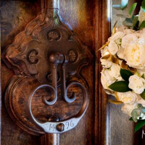 Close-up of the historic hotel door entrance together with the bride's white bouquet