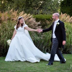 The couple taking a stroll in the gardens of their gorgeous historic venue during golden hour