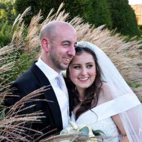 The newlyweds stand amongst the tall grasses for a portrait during golden hour at their Weston Manor Hotel wedding