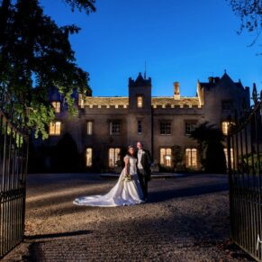 Floodlit night pose of the bride and groom under dusky blue skies on the long driveway outside the entrance to their Oxfordshire wedding venue