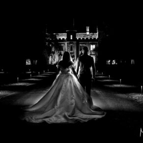 Atmospheric night shot of the newlyweds walking towards Weston Manor along the driveway after dark