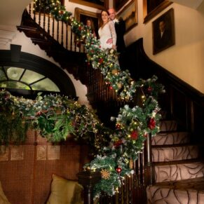 The newlyweds captured with atmospheric lighting on the Castle Hotel's Christmassy staircase on their wedding day in Windsor