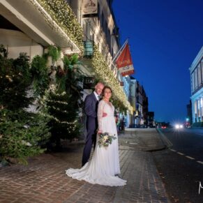 Photography of the newlyweds captured in front of the Christmassy Castle Hotel at dusk on their wedding day in Windsor