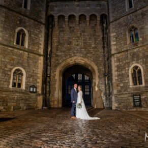 Photography of the newlyweds captured in front of Windsor Castle's dramatic main entrance after nightfall on their Castle Hotel wedding day