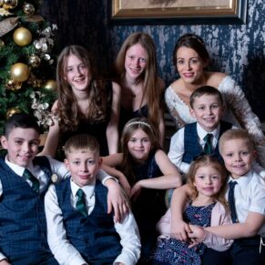 A group hug for this wonderful family pose next to the Christmas tree