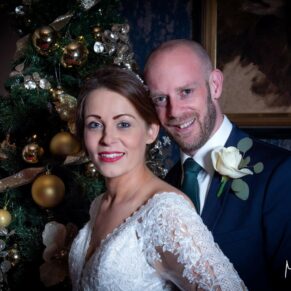 The happy newlyweds captured beside the Christmas tree on their festive wedding day