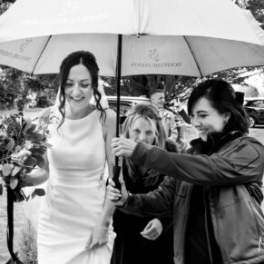 The bride arrives at Dovecote Events Barn during a summer shower