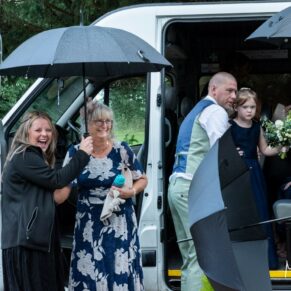 The bridal party arrive at the venue during a summer downpour