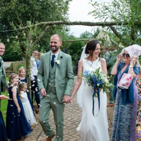 The newlyweds pick up speed as they dash through the confetti aisle just as the heavens open