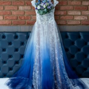 The bride's stunning blue and white wedding gown hanging above the bed pre ceremony at The Great House in Sonning