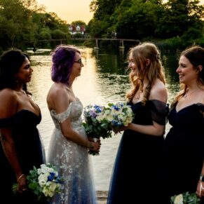 The bride with her bridesmaids on her wedding day at the water's edge during this magical summer sunset at the Great House in Sonning