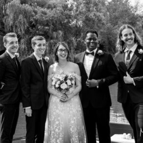 The newlyweds pose for the camera with their ushers next to the River Thames on their wedding day at The Great House in Sonning