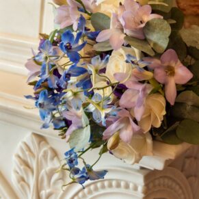 The colourful bride's wedding bouquet placed onto the marble fireplace surround at The Great House in Sonning