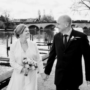 The bride and groom having a giggle as they stroll along the River Thames before their wedding reception