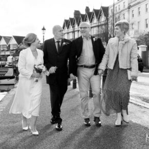 The bride and groom having a giggle with their witnesses as they stroll in the town centre before their wedding reception