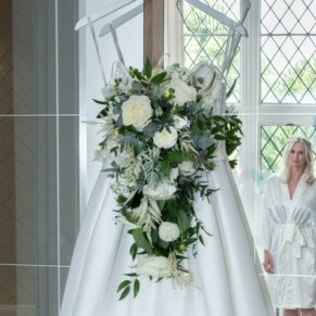 Photography of the wedding gown hanging up in the Bridal Suite on Latimer Estate with the bride seen in the mirror's reflection