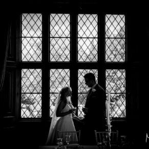 Dramatic silhouette portrait of the newlyweds in one of the leaded feature windows on the Latimer Estate