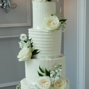 Photography of the stunning white floral arrangements on the yummy wedding cake located inside the Cavendish Suite on the Latimer Estate
