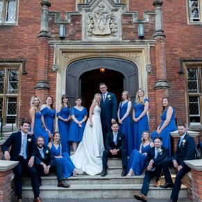 A classic group pose of the couple with their bridesmaids and ushers on the front steps at their Latimer Estate wedding
