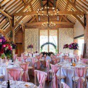Striking floral displays used throughout the historic barn interiors for this colourful wedding at Rackleys Barn in the Chilterns