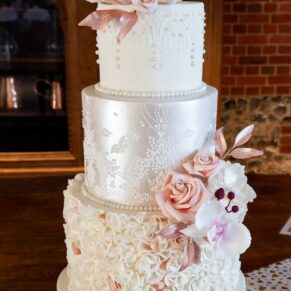 The divine multi tier iced wedding cake lit with soft window lighting at Rackleys Barn
