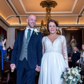 The smiling newlyweds exit their beautiful wedding ceremony in the grand surroundings of The Guildhall in Windsor