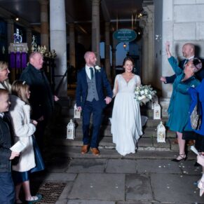 The newlyweds walk through a night time confetti aisle after their civil ceremony at the Guildhall