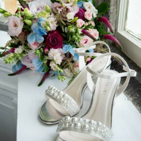 The brides shoes and bouquet rest on the window sill prior to her wedding ceremony at Bisham Abbey