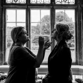 The bride has adjustments made to her make-up in readiness for her Bisham Abbey marriage ceremony