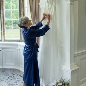 Photography of the bride as she makes adjustments to her gown in readiness for her Bisham Abbey summer wedding ceremony