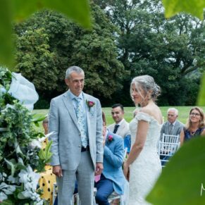 The celebrant led wedding ceremony captured through the trees at Bisham Abbey in Marlow