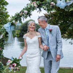 Photography of the newlyweds enjoying a giggle at their Bisham Abbey wedding reception next to the River Thames